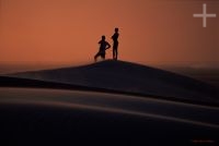 Man and boy on the sand dunes, sunset, Parnaiba, Brazil